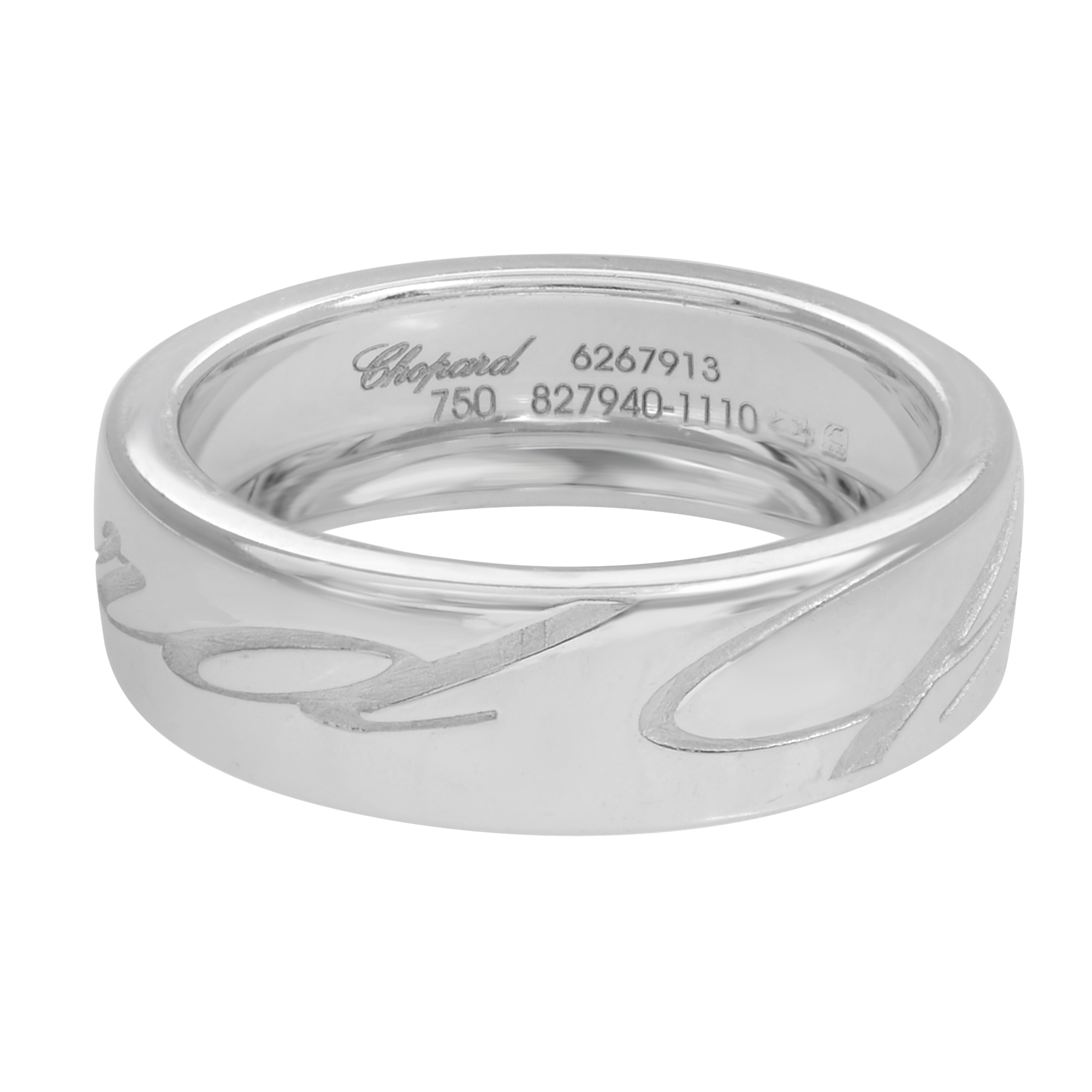 An image of a Chopard Chopardissimo Ethical women's ring without stones, showcasing a polished white gold band with a slight reflective sheen. The ring is positioned at a three-quarter angle, allowing visibility of the inner and outer surfaces. The inner band is engraved with the Chopard brand name, a serial number, and hallmark indicating its metal purity. The outer band features a cut-out design, adding a decorative element to the simple, elegant piece. The ring occupies the center of the image, with a close-up view that emphasizes its details and craftsmanship.The ring is pre-owned and in great condition.