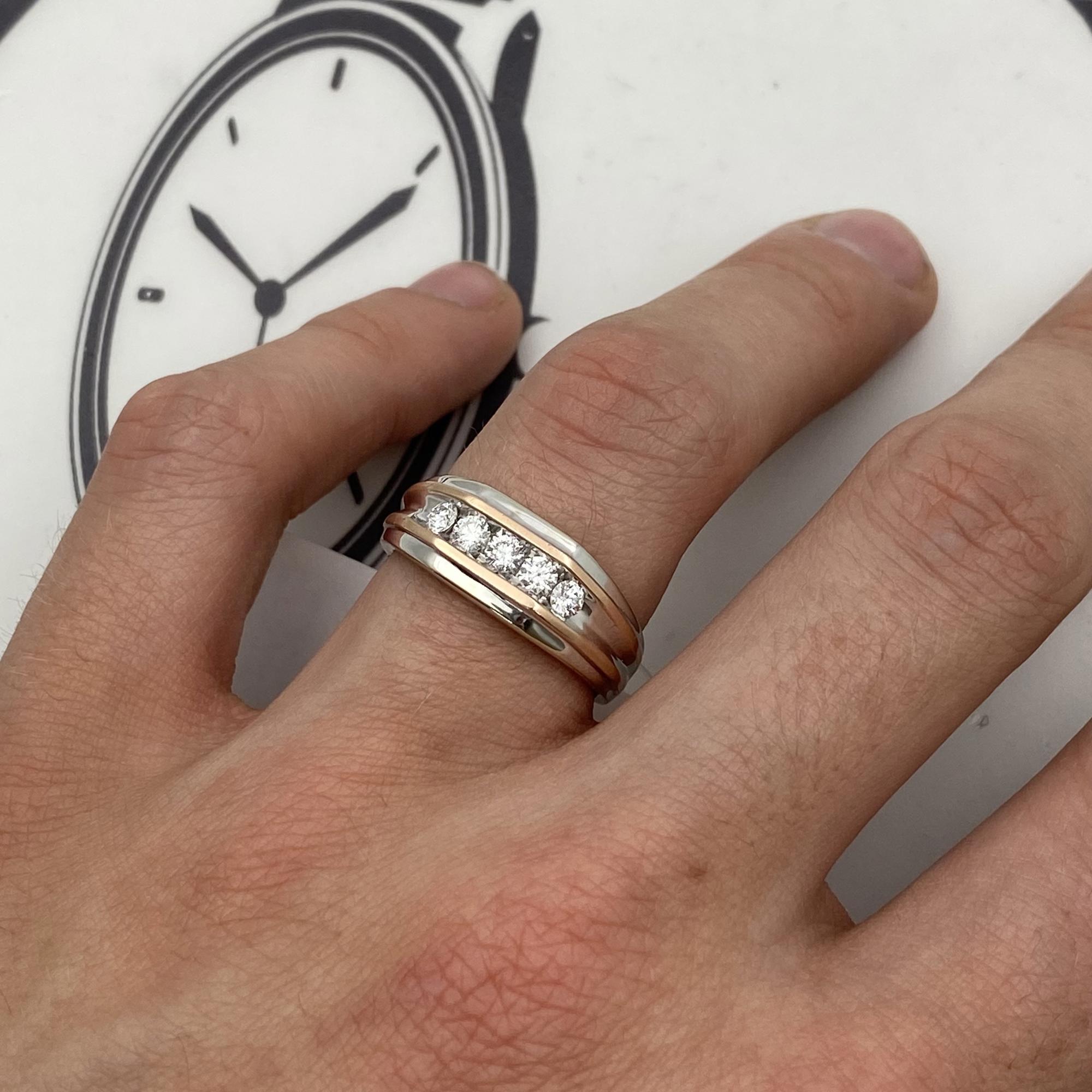 An image of a Rachel Koen men's wedding band with diamonds displayed on a finger, viewed from a top-down angle. The ring features a central band of sparkling diamonds set between two smooth gold bands. The image is a close-up, showing the ring in sharp detail against the backdrop of a hand and a blurred clock face.