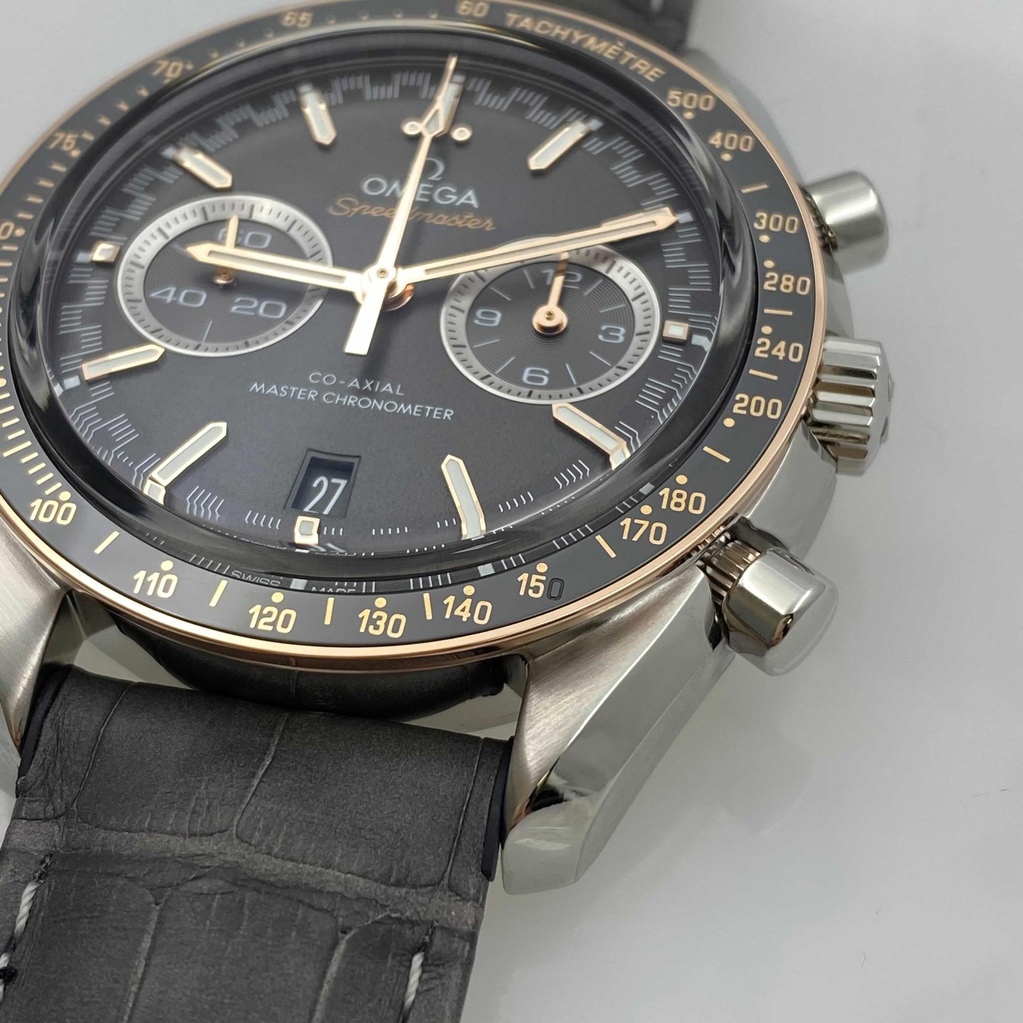 An image of an Omega wristwatch positioned at an angle showcasing the right side of the watch face, focusing on the chronograph and small seconds subdial. The watch is in new condition with defects and features a grey leather strap. The photograph is taken at a close distance, highlighting the intricate details of the dial and the watch's silver and gold accents.