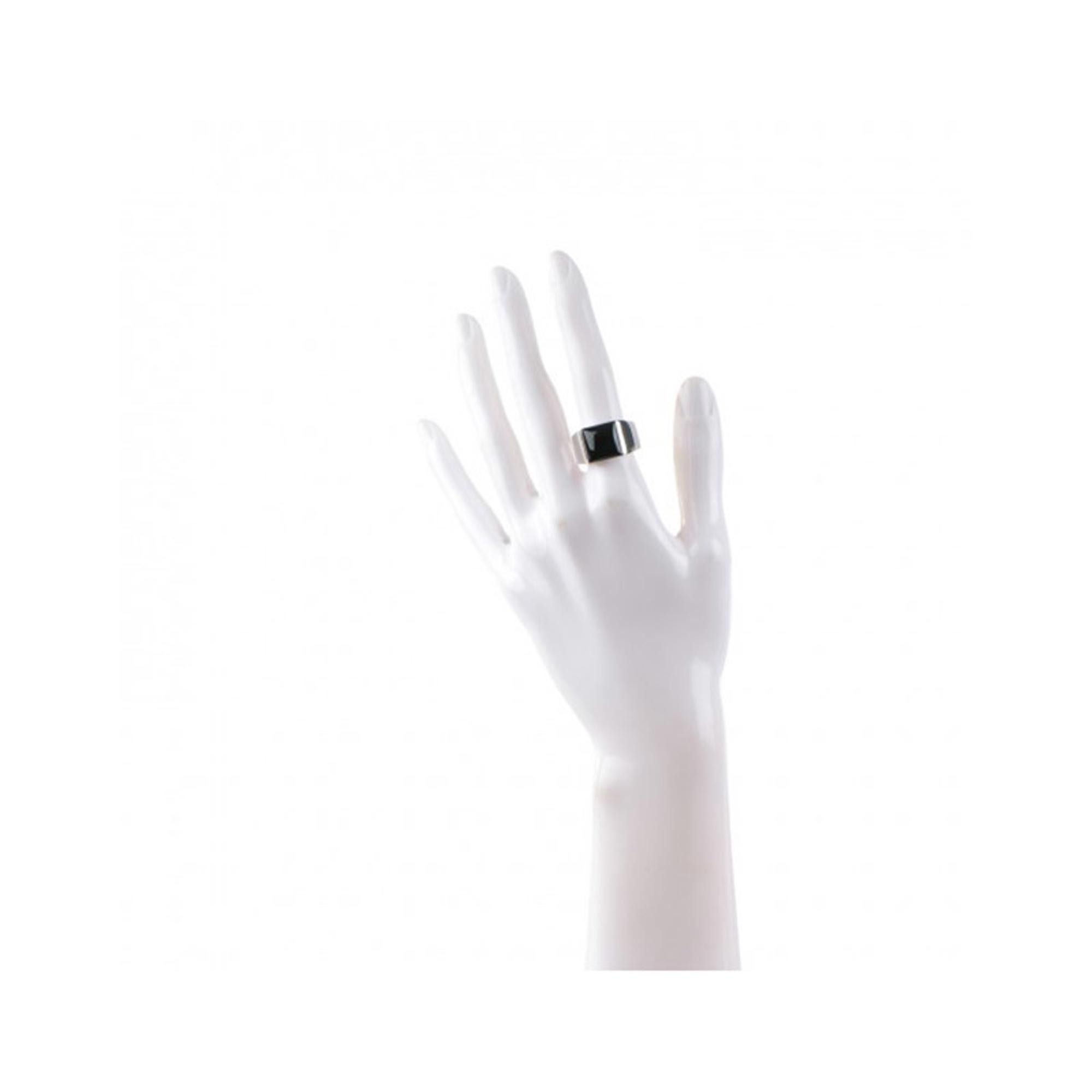 An image of a unisex adult Cartier ring with gemstone, displayed on a white mannequin hand. The hand is shown in an upright position with fingers gently spread, and the ring is worn on the ring finger. The band appears wide with a polished finish in white gold, and the Onyx gemstone is visible on top, centered and reflecting light. The perspective is a front-facing view with the ring at a medium distance, allowing for a clear view of both the ring and the hand. Great preowned condition.