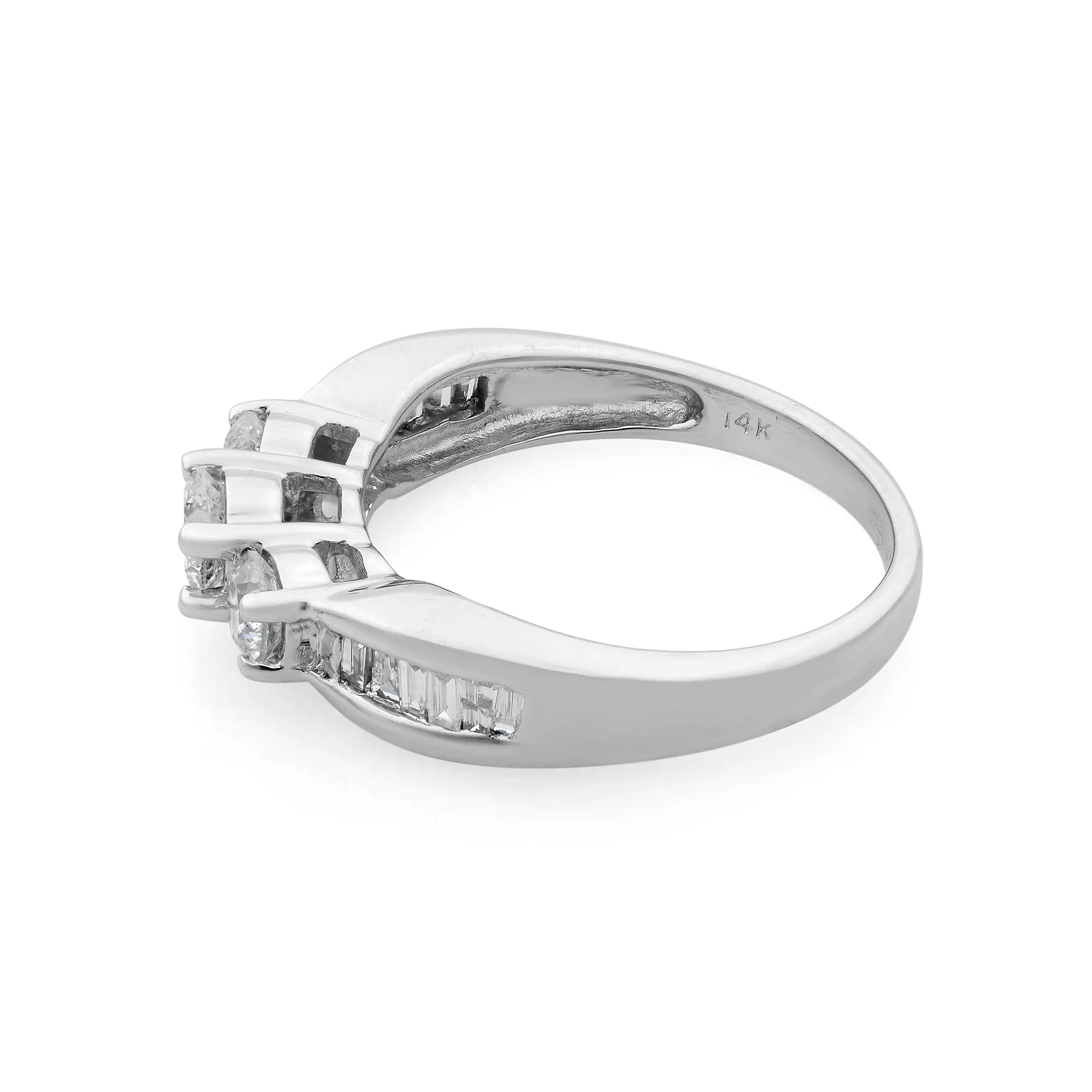 An image of a Rachel Koen brand ring for women, showcasing a 14K white gold band with a series of channel-set baguette diamonds. The ring is photographed at a slight angle from above, positioned to the left, with the diamonds aligned diagonally across the top of the band. The focus is on the upper side of the ring, providing a clear view of the diamonds and the band's polished surface. The background is a neutral white, emphasizing the ring's design and sparkle.The ring is pre-owned in a great condition. 