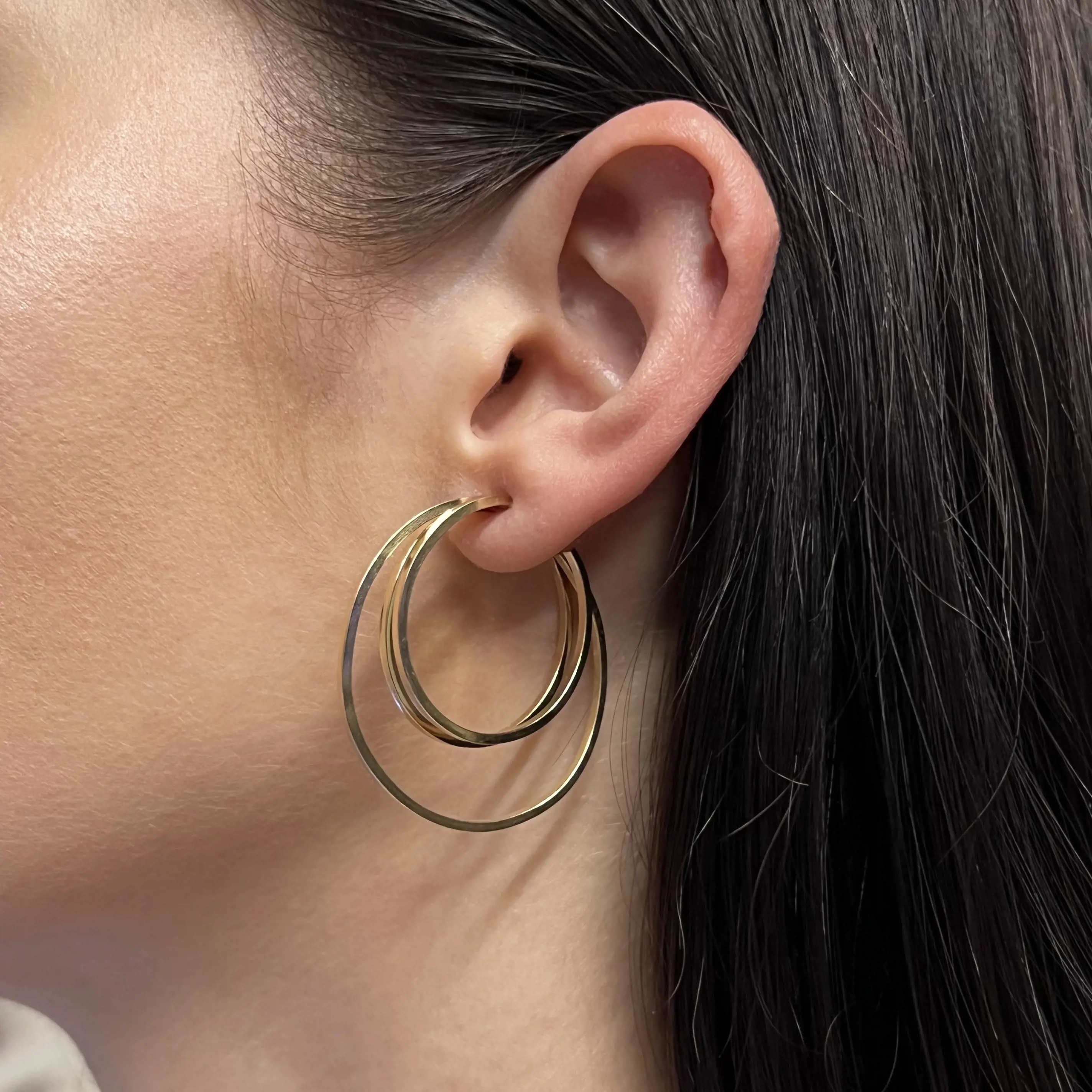 An image of a woman's ear wearing a Rachel Koen earring without stones. The earring is a simple, elegant hoop design, captured from a close-up side angle. The earring hangs gracefully from the earlobe, emphasizing its smooth, yellow gold finish.Excellent pre-owned condition. 
