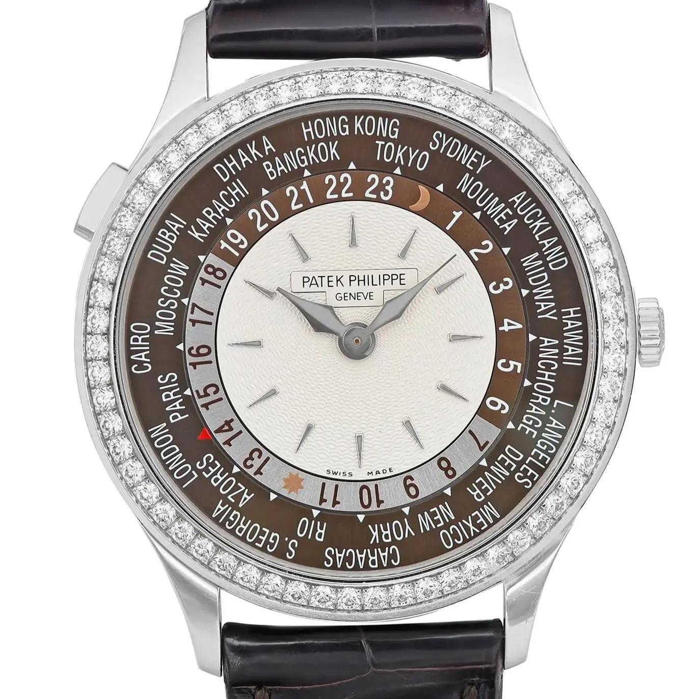 An image of a pre-owned wristwatch taken from a front close-up angle, focusing on the watch face. The watch features a detailed dial with multiple time zones, surrounded by a diamond-encrusted bezel. The hour and minute hands are sleek and metallic. The watch's brand name is displayed prominently on the face. The strap is visible at the top and bottom, made of a dark, glossy material.