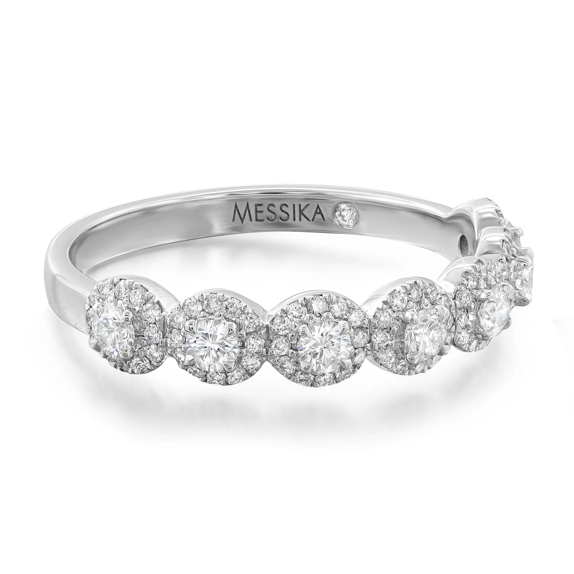 An image of a Messika women's ring with diamonds, displayed at a slight angle to show the circular diamond-encrusted design along the top half of the band. The brand name "MESSIKA" is engraved on the lower side of the ring's polished silver band, which is visible in the foreground. The ring is centered and shown up close, highlighting the sparkle and intricate setting of the diamonds.