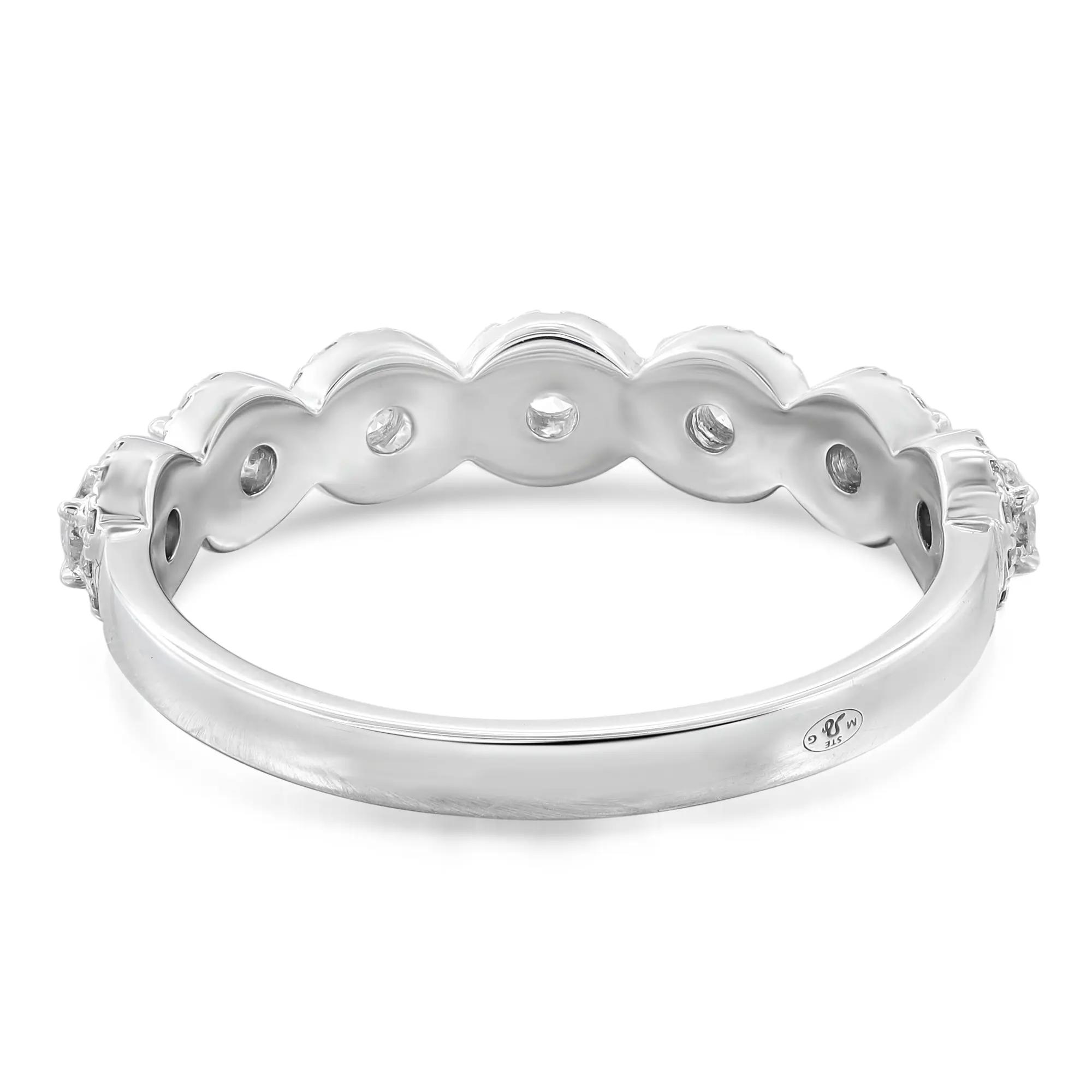 An image of a Messika brand women's ring with diamonds, displayed at a slight angle to showcase the intricate design and diamond placement. The band is polished white gold with a scalloped edge and several small, round diamonds set equidistant along the top half. The ring is centered and occupies the middle ground of the image, providing a clear view of its craftsmanship. The background is a neutral white, emphasizing the ring's details and reflective qualities.