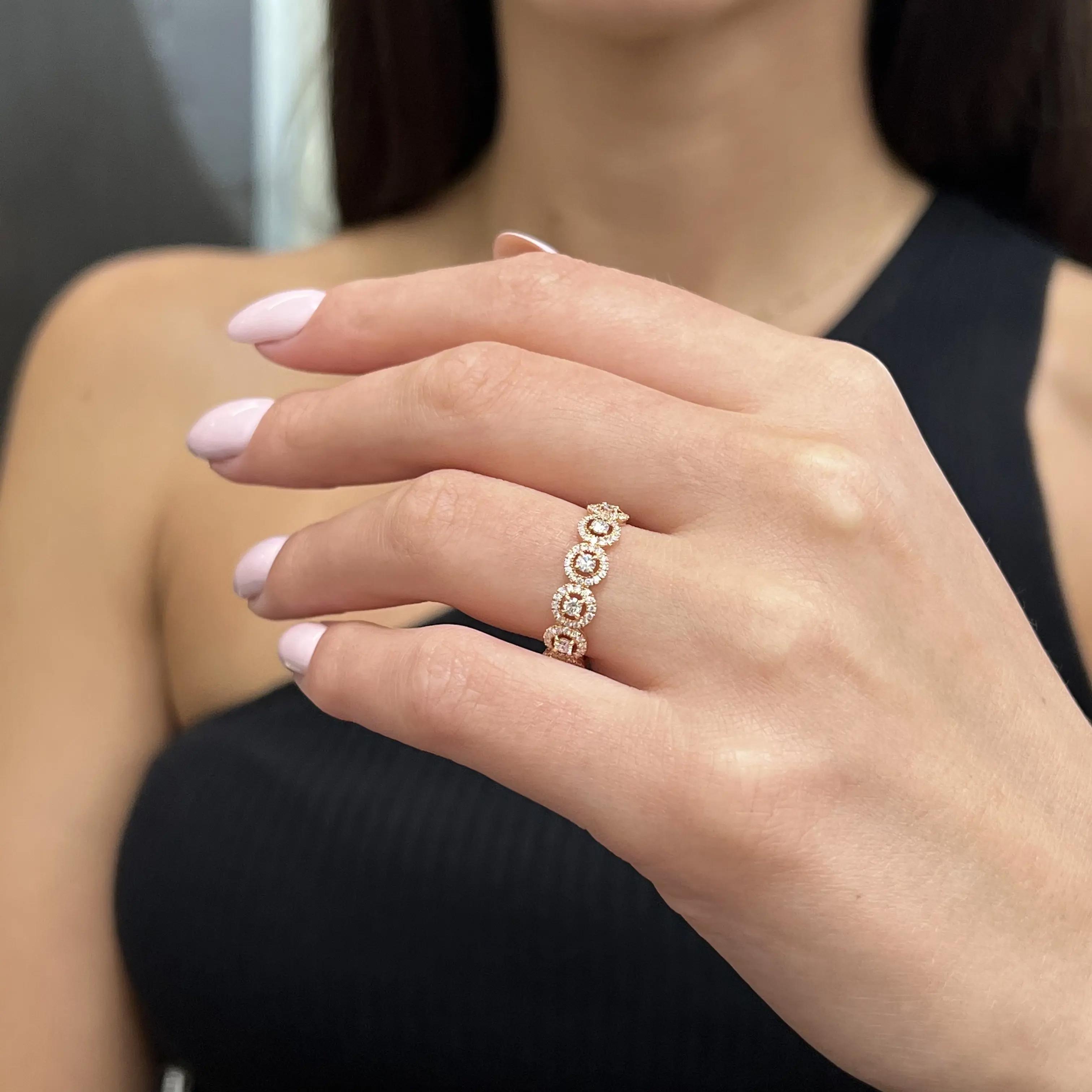 An image of a Messika brand ring with diamonds displayed on a woman's finger, centered and in sharp focus. The ring features several prominent diamonds set in a rose gold band. It is viewed from a side angle, showcasing the sparkle of the diamonds and the design of the band. The background is blurred, with the ring being the main object of attention at a close but comfortable distance, allowing for detailed observation of its design and craftsmanship.