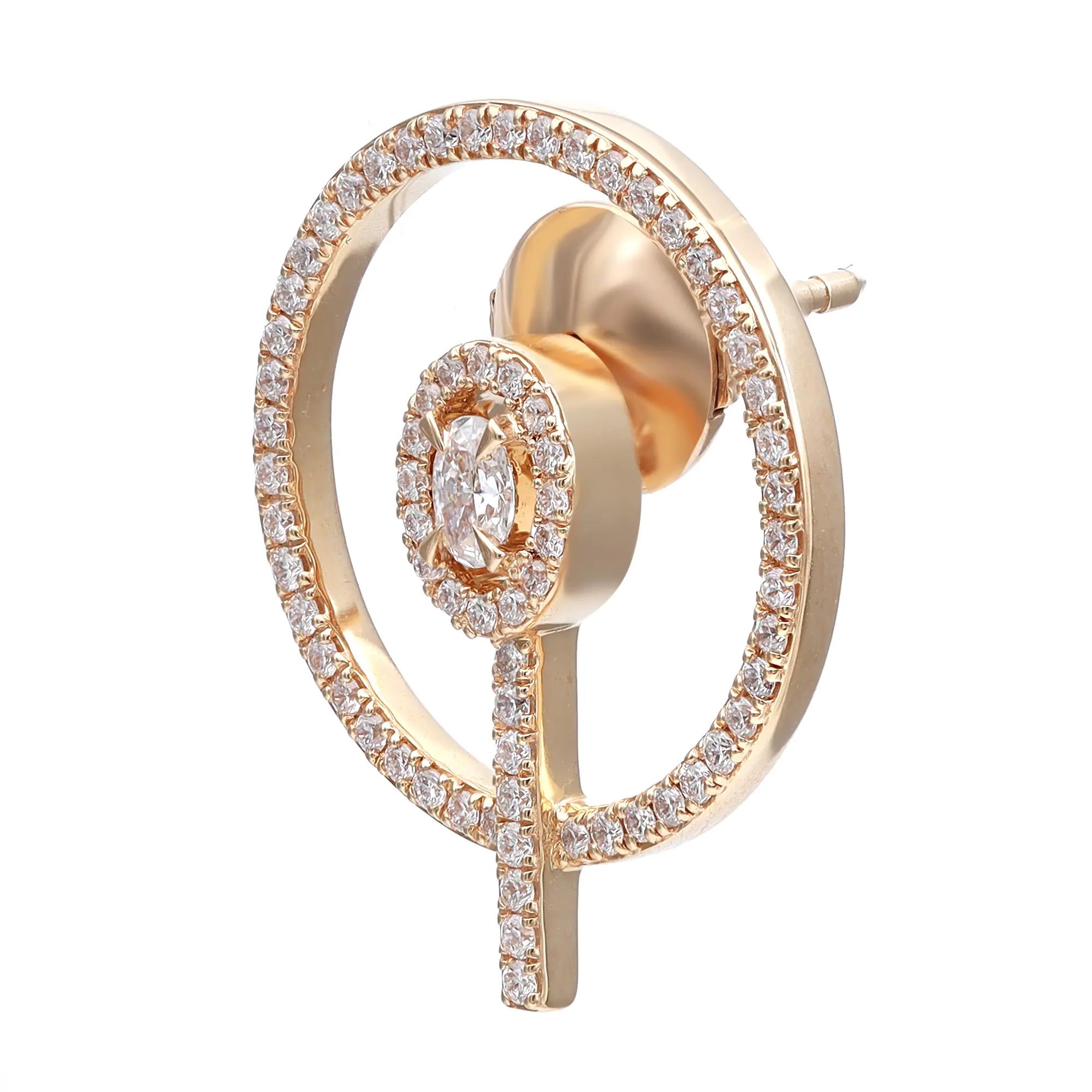 An image of a Messika women's earring with diamonds, displayed in a close-up side view. The earring features a large circular hoop design, encrusted with small diamonds along its circumference, and a smaller circular diamond cluster set at the lower part of the hoop. A straight bar with diamonds extends from the bottom of the smaller circle down the hoop's center, creating a symmetrical design. The earring is positioned against a white background, highlighting its golden metallic sheen and the sparkle of the diamonds.