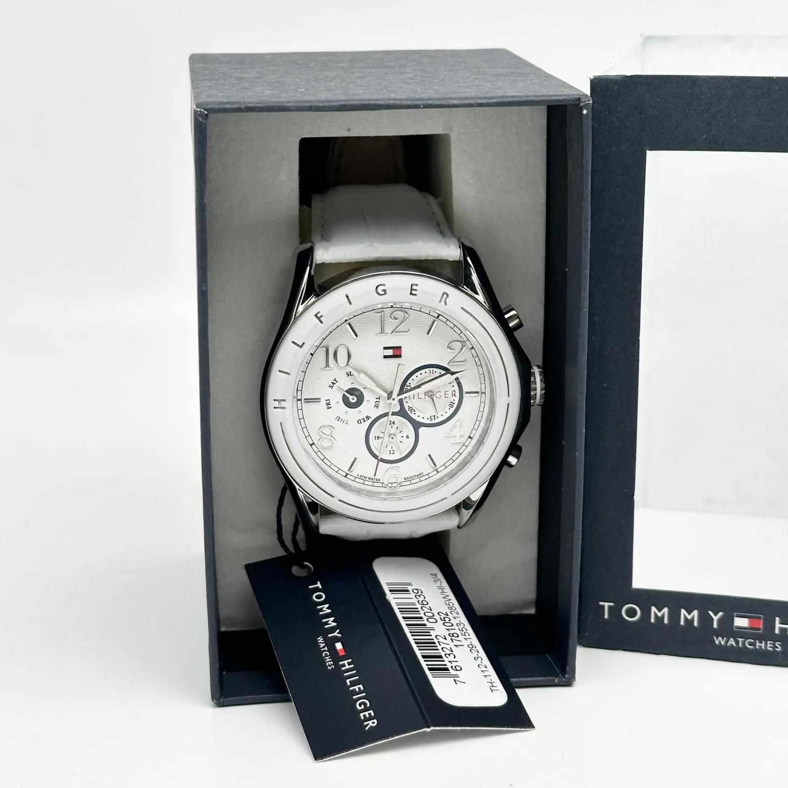 An image of a Wristwatch by Tommy Hilfiger. This Unworn item is designed for Men, featuring a Casual style. It has a Quartz movement and an Analog display with a White dial color. The indices include 12-Hour Dial,Arabic Numerals,Stick Indexes. The band is made of Leather and the case is made of Stainless Steel. The watch has a Round shape with a case size of 45 and a case thickness of 12 mm.