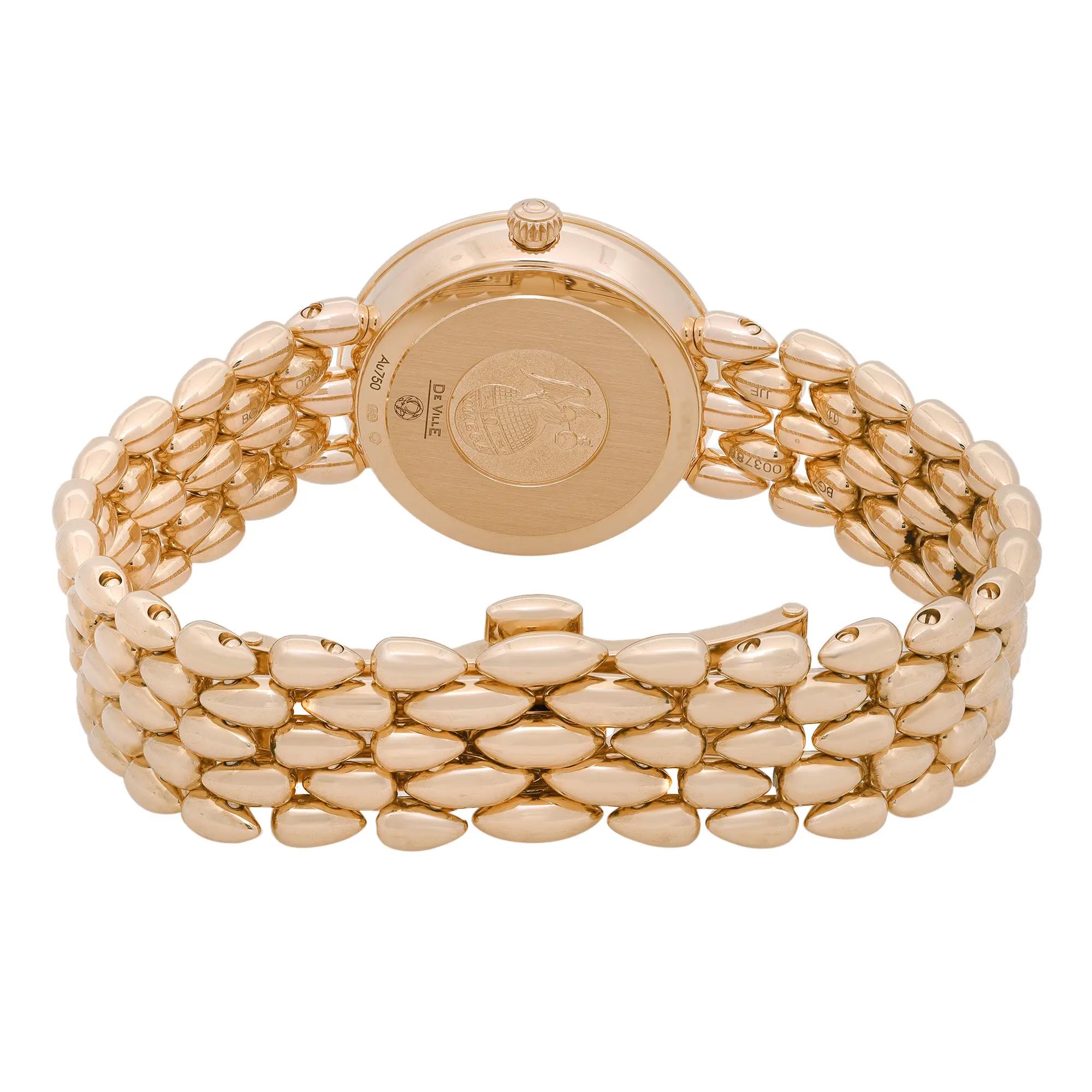 An image of a wristwatch taken from the back view, focusing on the closed clasp. The watch is a display model with a polished gold bracelet featuring an intricate, rounded link design. The case back is prominently visible, engraved with detailed markings. The shot is taken from a close distance, highlighting the texture and craftsmanship of the watch.