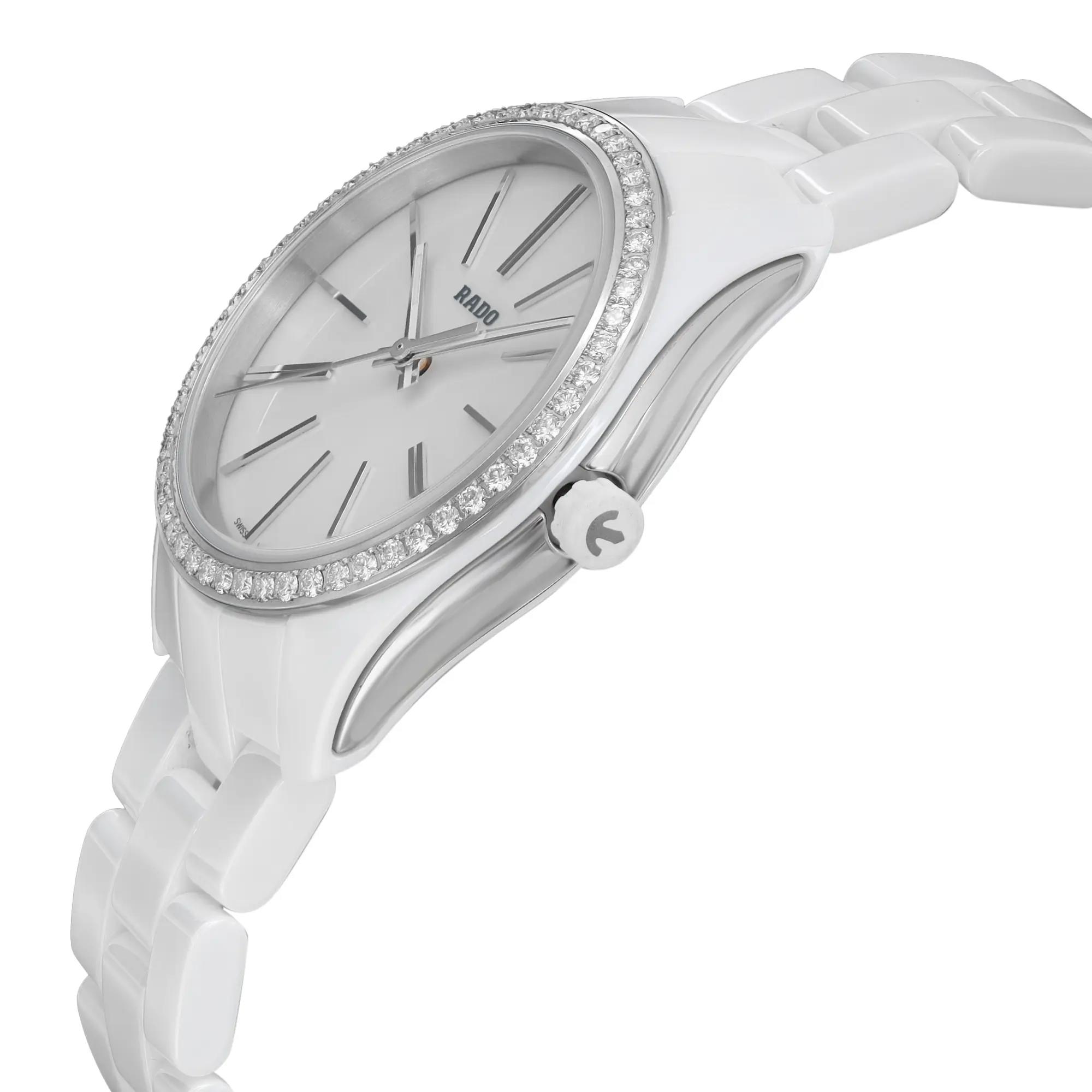 An image of an unworn Rado women's wristwatch in a casual style, captured from a side profile angle that highlights the crown. The watch features a round shape with a white dial and diamond bezel, accented by luminous hands. It is constructed with a ceramic band and case, complemented by stainless steel elements. The watch is positioned at a mid-distance, providing a clear view of the details and craftsmanship.