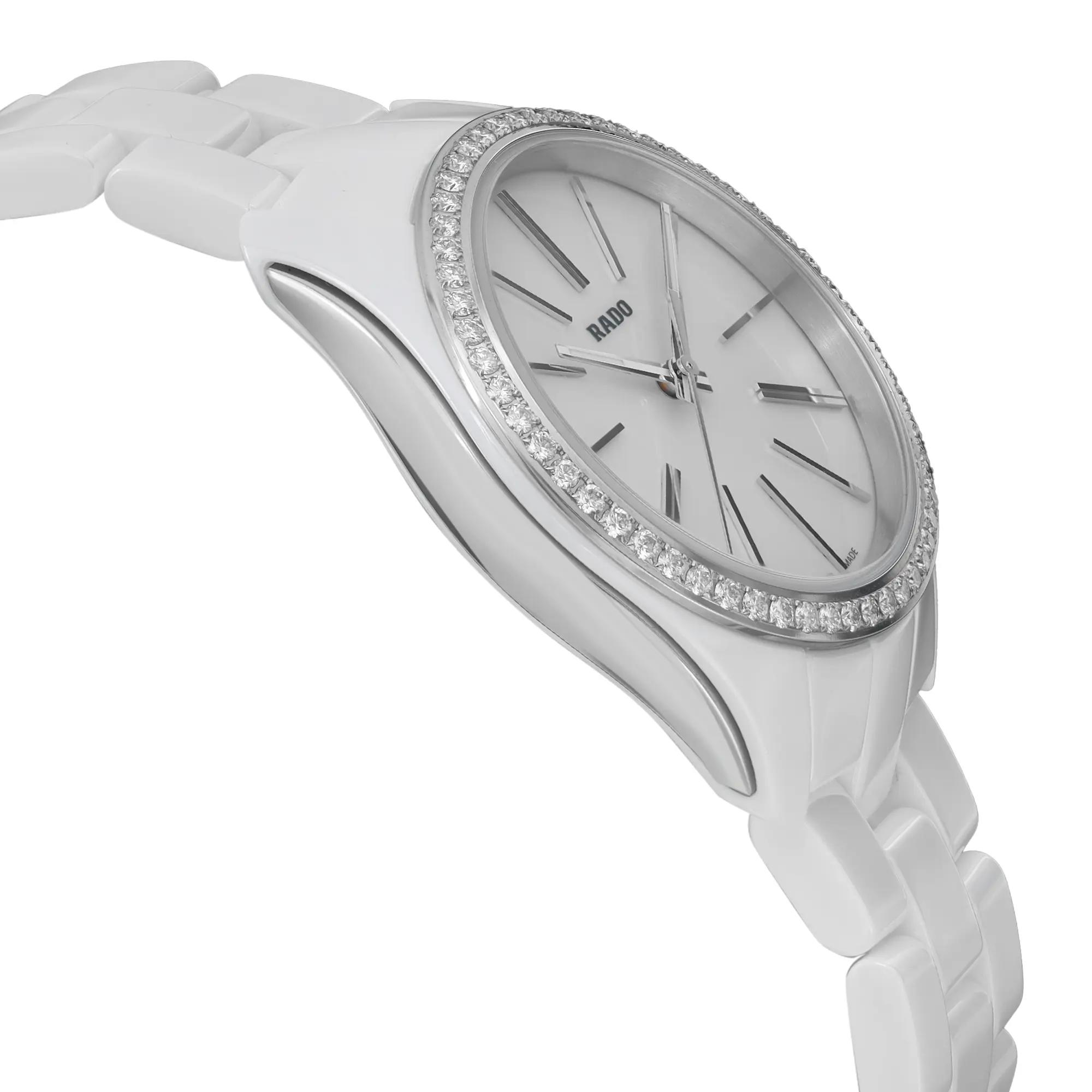 An image of an unworn Rado women's wristwatch in a side profile view opposite of the crown, showing a white dial with luminous hands, gray bezel adorned with diamonds , and a ceramic band. The case, made of ceramic and stainless steel, is round. The overall style is casual and the watch is positioned at a slight angle, with a close-up perspective that reveals the texture and detail of the materials.