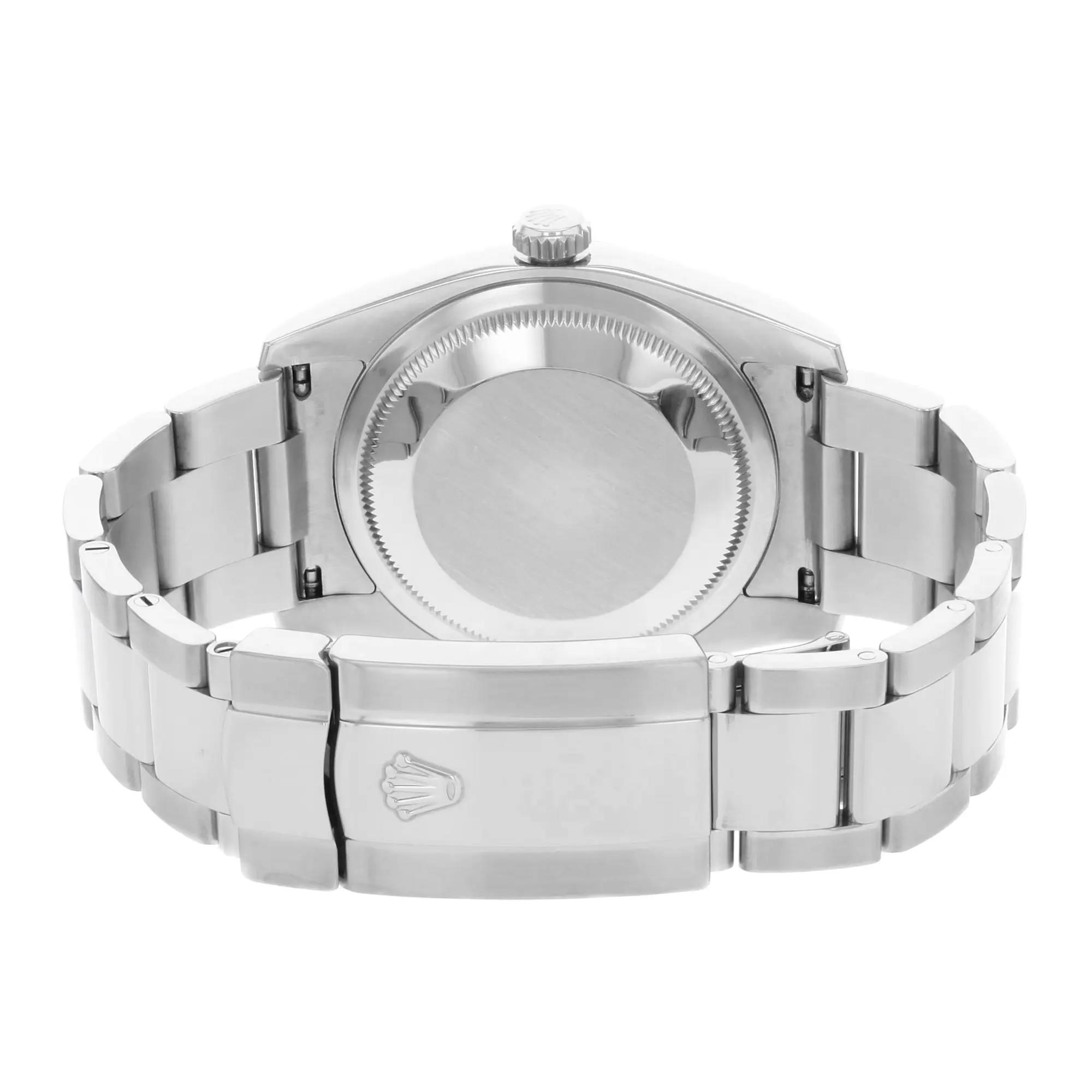 An image of a pre-owned wristwatch showing the back view with a focus on the closed clasp. The watch is positioned horizontally, displaying the polished metal links of the bracelet and the smooth, round case back. The clasp is centrally located and prominently features a logo. The angle captures the watch from a slightly elevated perspective, providing a clear view of the details, and the image is taken from a close distance.