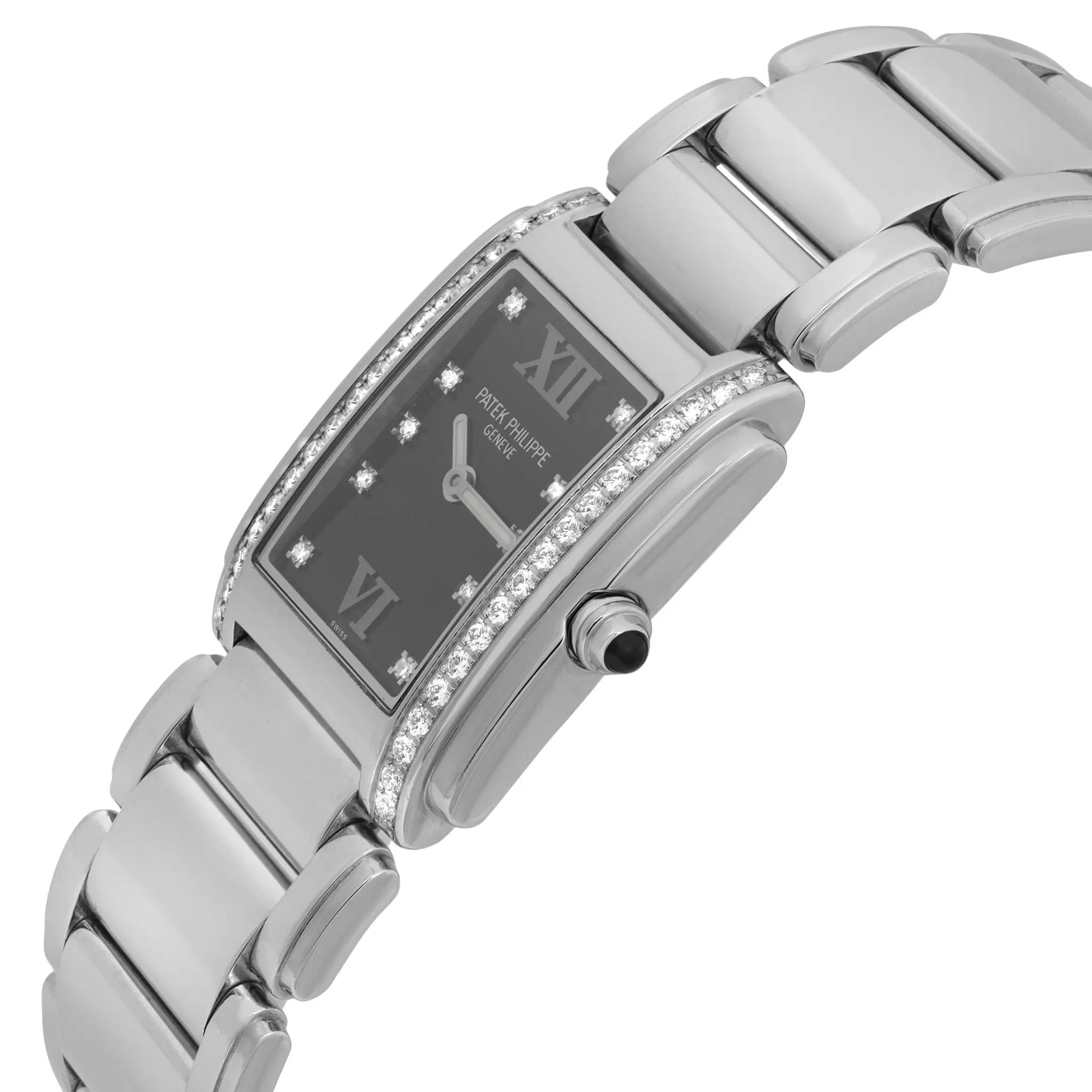 An image of a pre-owned Patek Philippe women's wristwatch, viewed from a slight angle, highlighting the elegant rectangular face. The watch is positioned at a close distance, showcasing its luminous hands and diamond-set bezel. The stainless steel band is partially visible, emphasizing the watch's luxurious design.
